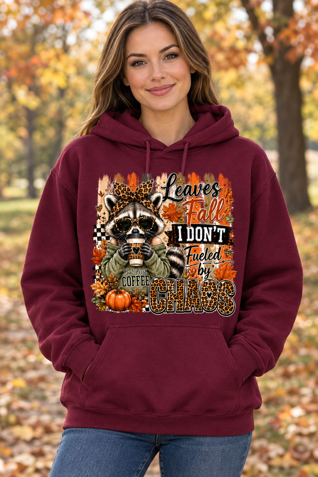 AI-generated model mockup of a woman wearing the burgundy Leaves Fall, I Don't hoodie with the raccoon and Fueled by Chaos graphic.