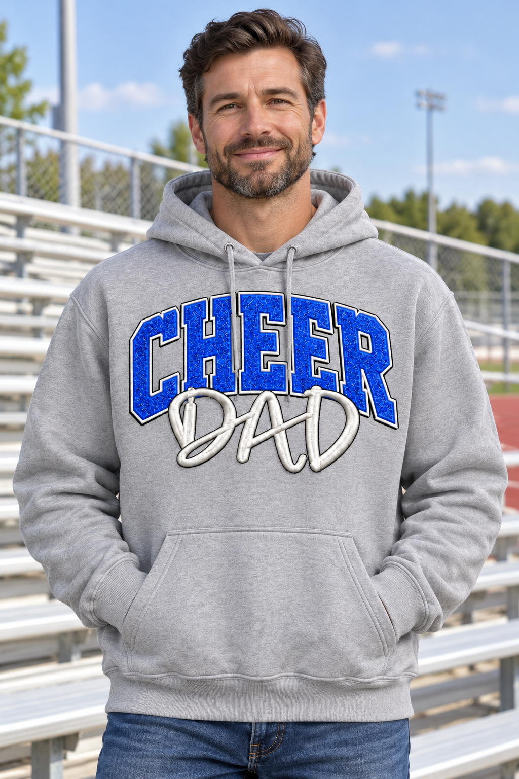 AI-generated model mockup of a man wearing a gray Cheer Dad hoodie with blue CHEER lettering and white DAD script.